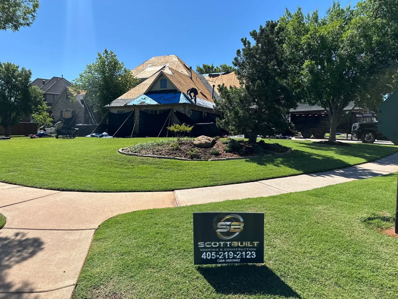 ScottBuilt Roofing & Construction crew replacing roof on upscale Oklahoma home with yard sign